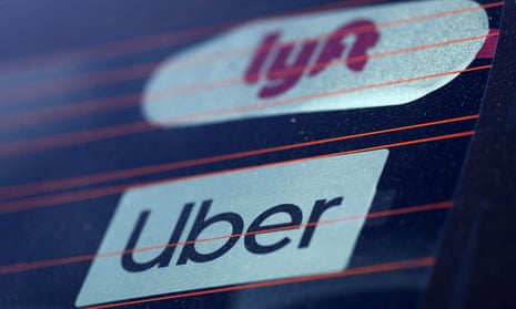 Uber and Lyft signs are seen in a car's windshield