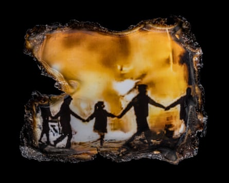 A photograph shows people in silhouette holding hands around a bonfire. The edges of the photo are blackened and burned.