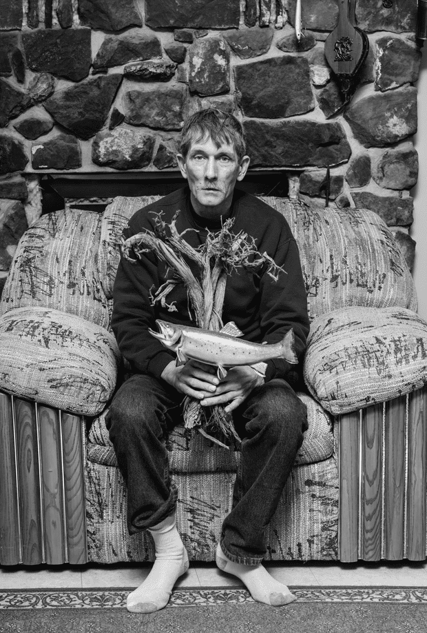 A man holding a stuffed fish on an overstuffed armchair
