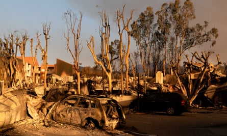 The sun casts a golden glow on the remains of vehicles and buildings destroyed by the Palisades fire in Los Angeles, California
