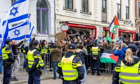 Police cordons separate groups of protesters, one group waving Israel flags and the other Palestine flags.