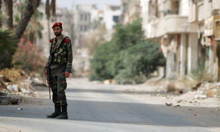 A Syrian army soldier stands at the entrance of the besieged Damascus suburb of Darayya, before the evacuation of residents and insurgents started on Friday.