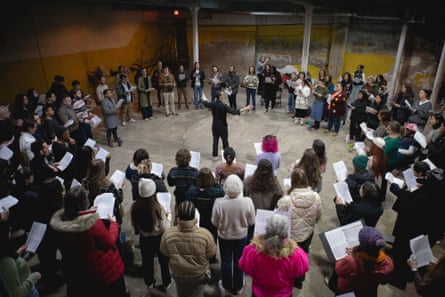 A group of group who are singing and holding expanse euphony encircle a conductor