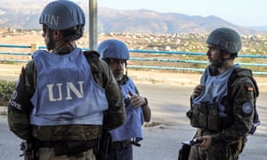 Three UN peacekeepers in helmets and fatigues