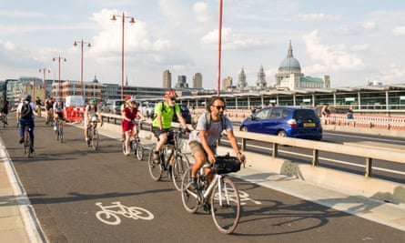 Cyclists commuting on the CS6 cycle superhighway on Blackfriars Bridge at rush hour with St. Pauls Cathedral in background