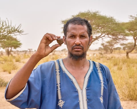 Khouna Ould Ahmedou, wearing a blue kaftan, holds up a small rock