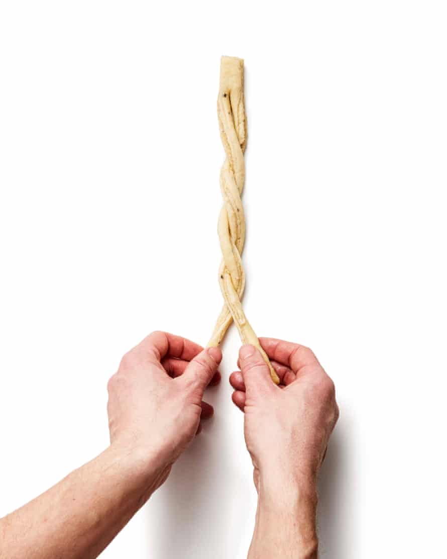 Felicity Cloake’s perfect cardamom buns – step 7a. Cut the strips almost, but not quite, in half widthways, so they look a bit like pairs of trousers, stretch the “legs” slightly, then twist these strips together like plaits.