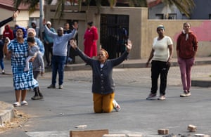 People in the middle of a street raise their arms in a gesture of surrender