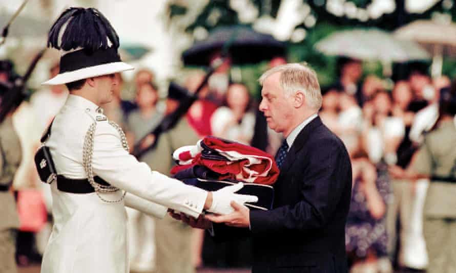 Chris Patten, el vigésimo octavo y último gobernante del Hong Kong colonial, recibe la bandera Union Jack después de que se bajara por última vez en la Casa de Gobierno en 1997.