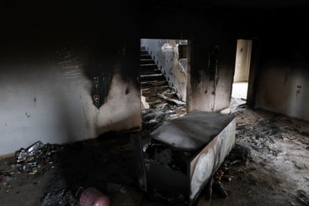 A fire-damaged and part-destroyed downstairs room with debris strewn and broken stairs.