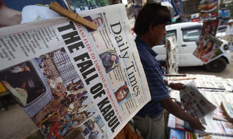 People read front page news of Taliban taking over Kabul, at a newspaper stall in Karachi, Pakistan.