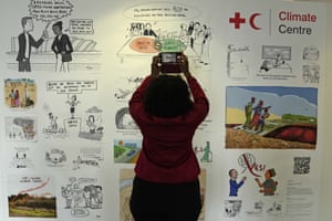 A woman takes photos of climate change cartoons at the Cop26 venue