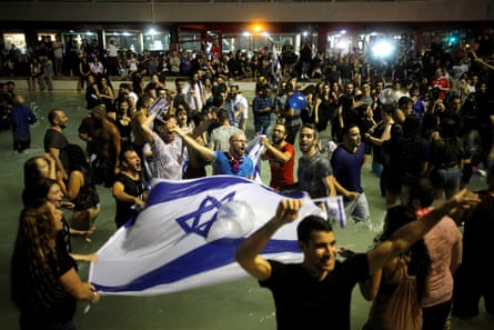 people celebrate outside and wave the Israeli flag