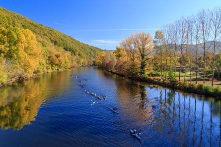 Autumnal trees, deep blue river and canoeing