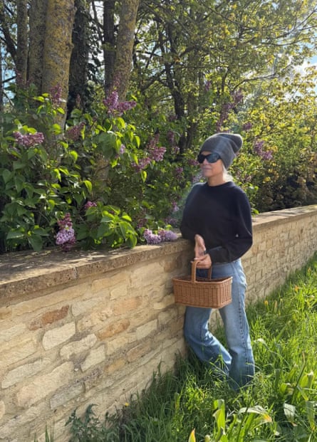 woman leaning on wall in garden wearing hat