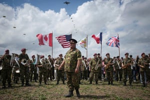 Army musicians play wind instruments as a parachute drop takes place