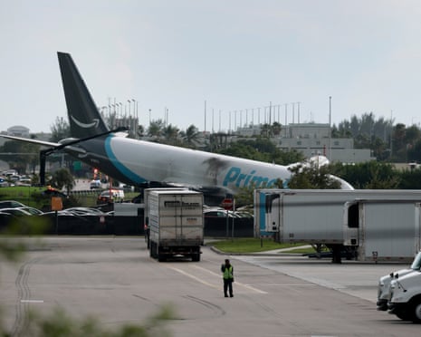 A cargo plane with scorched fuselage rests off the runway after crashing at Miami airport