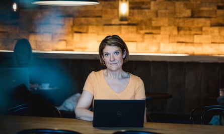 Andrea sits at a table with her laptop in a coffee shop.