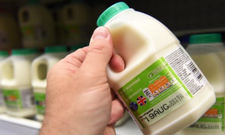 A hand holding a pint of milk in a plastic bottle.