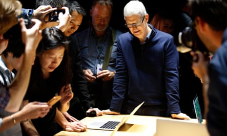 Tim Cook, CEO of Apple, looks on as guests inspect a new MacBook Pro
