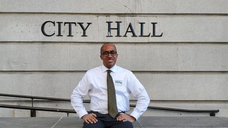 man in white shirt with tie smiles with hands on hips