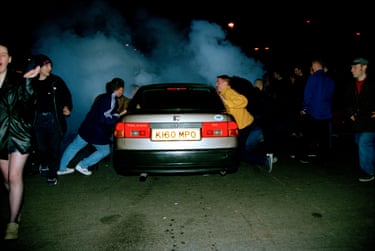 People leaning against a car at night
