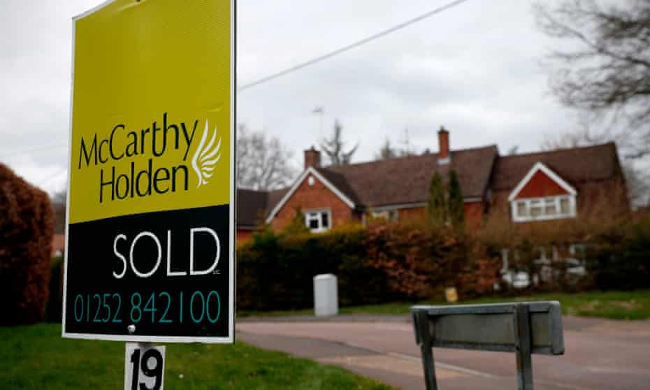 Estate agent sign reading 'sold' outside large house