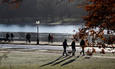 Early morning walkers cast long shadows in Hyde Park in London