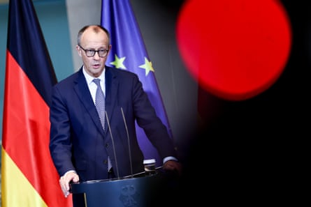 Friedrich Merz at a podium with the German and Europe flags in the background