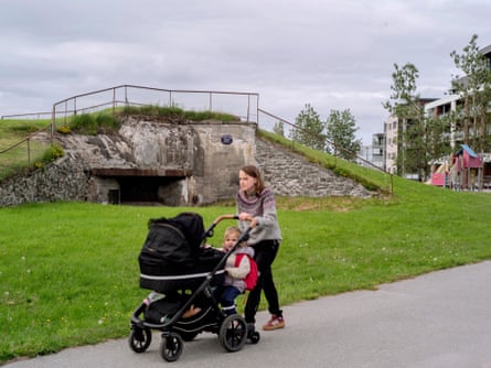 A woman walks with a pram past the entrance of an old war bunker in Bødo, Norway.