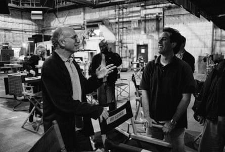 Jerry Seinfeld and Larry David laugh and talk near director’s chairs on set