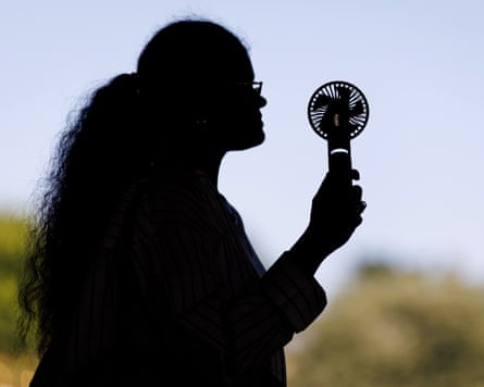 Silhouette of a person using a handheld fan