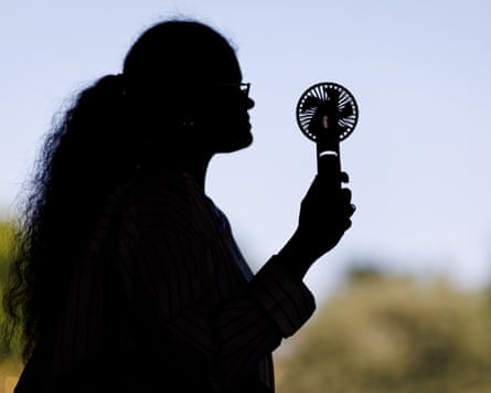 A person uses an electric fan to cool down during a heatwave in London