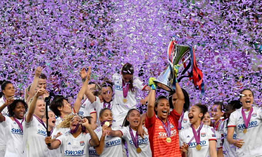 Lyon players celebrate with the trophy under a downpour of purple paper after the Champions League final of 2019