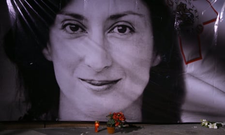 Flowers and a candle lie in front of a portrait of the Maltese journalist Daphne Caruana Galizia