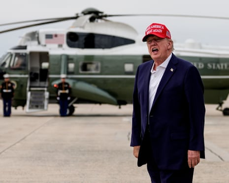 a man in a suit and red cap yells with helicopter in background