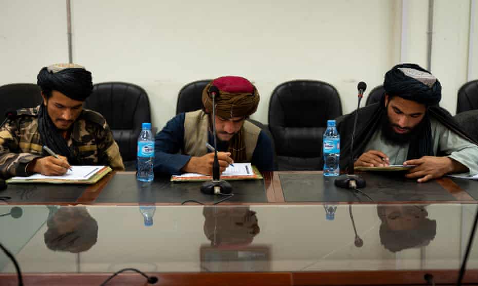 Three Taliban members in traditional outfits sit writing at a desk in Kandahar, southern Afghanistan.