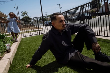 Man in black in yard with little girl in dress behind him