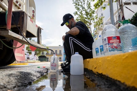 A man filling h2o containers from a tanker truck