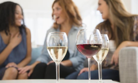 Women drinking wine and talking on sofa in living room
