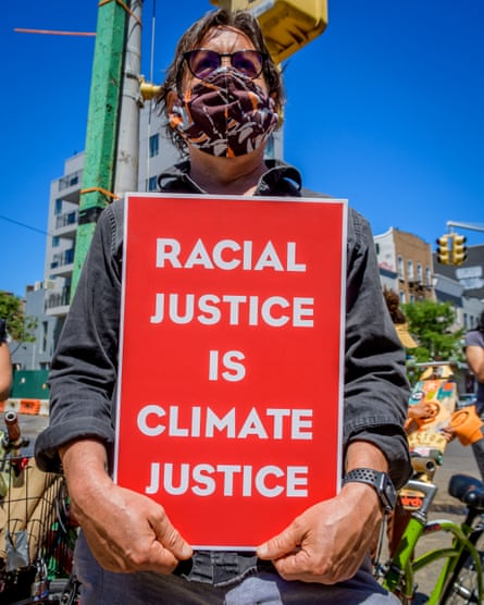 A man holds a sign at a protest in Brooklyn. Some climate activists believe the changes needed to address climate change are in line with the ones that will bring racial justice.
