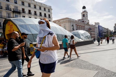 A woman uses a face mask to cover from the sun as she walks at Puerta del Sol Square in Madrid, Spain.