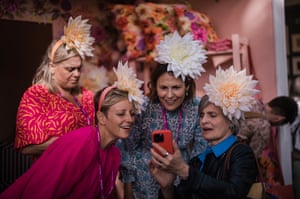 Four women take a selfie together, each wearing a huge flower hat