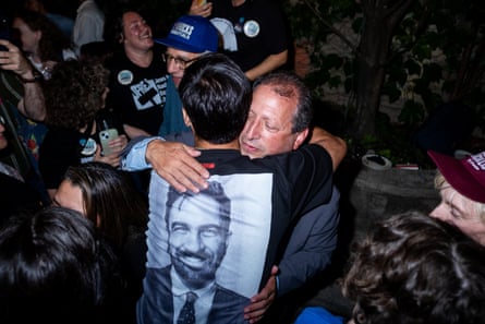 a man hugs a supporters who is wearing a t-shirt with Zohran Mamdani’s face on it