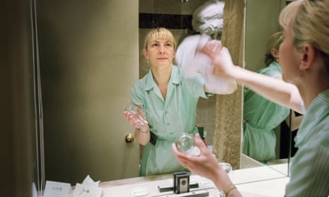 A cleaner polishing a mirror in a London Hotel.