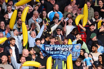 Manchester City fans hold a banner reading ‘In Khaldoon we trust’ and inflatable bananas