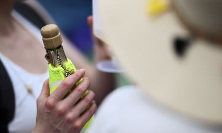 A member of the public drinks champagne at the All England Tennis club in Wimbledon.