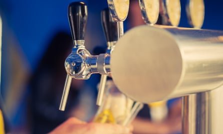 A barman pours a pint of lager from the tap