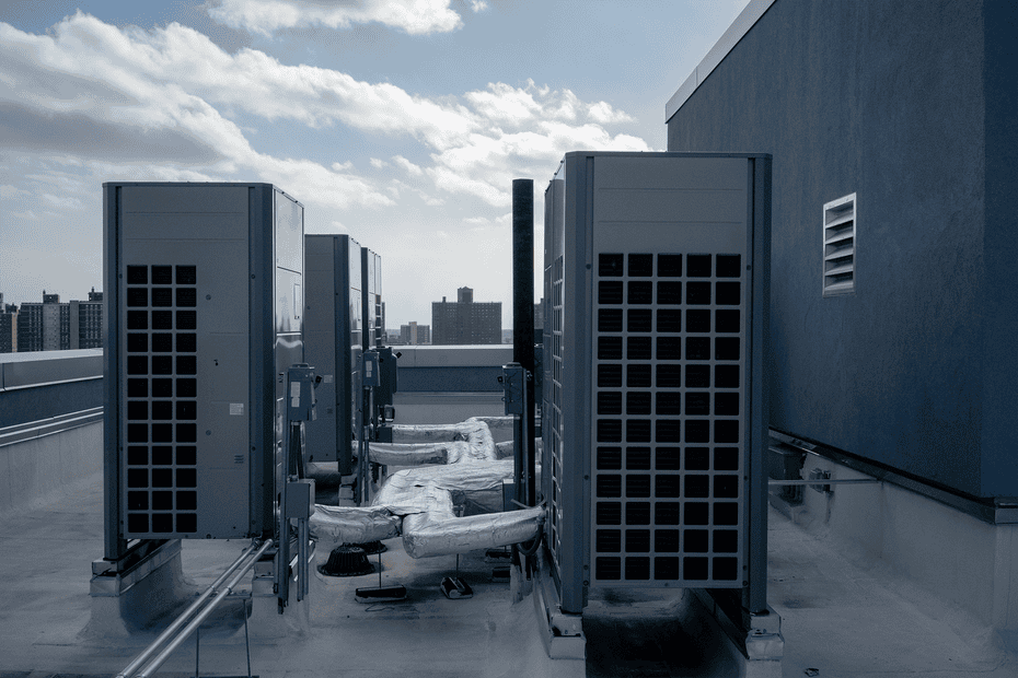 Large blue-gray air ventilation systems sit on a rooftop, with the city skyline in the background.