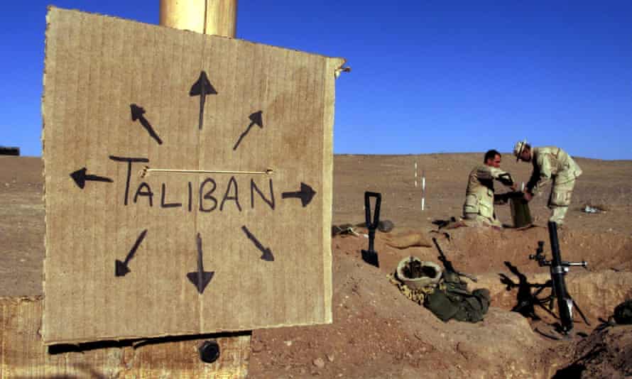 US Marines near a cardboard sign reminding everyone that Taliban forces could be anywhere